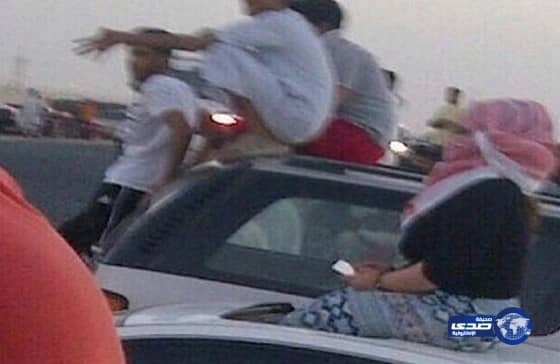 فتاة تتجمهر مع عدداً من الشبان لمشاهدة عرض تفحيط